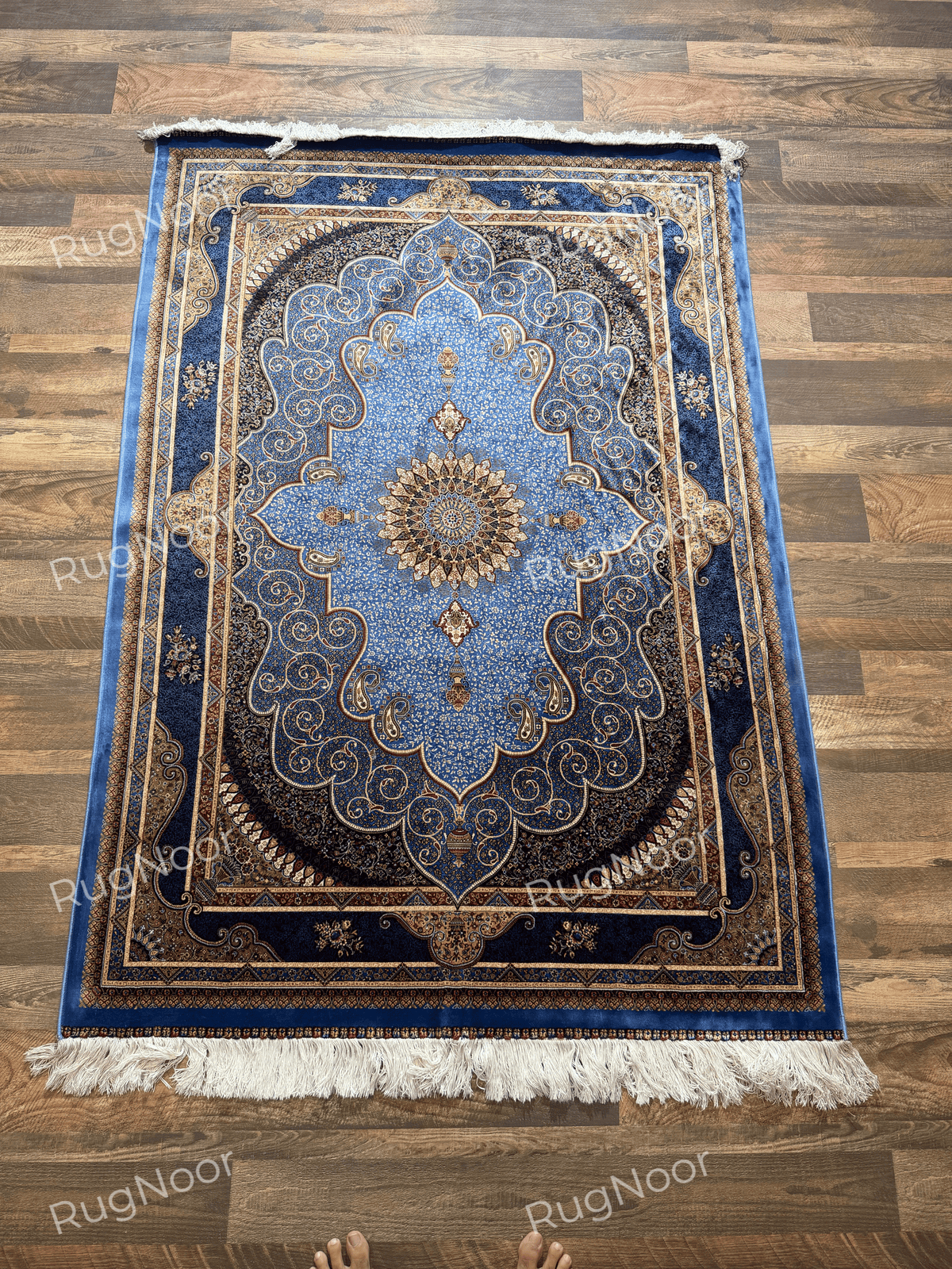 Full view of Yasamin showing its blue floral field, layered borders, and ivory fringe.