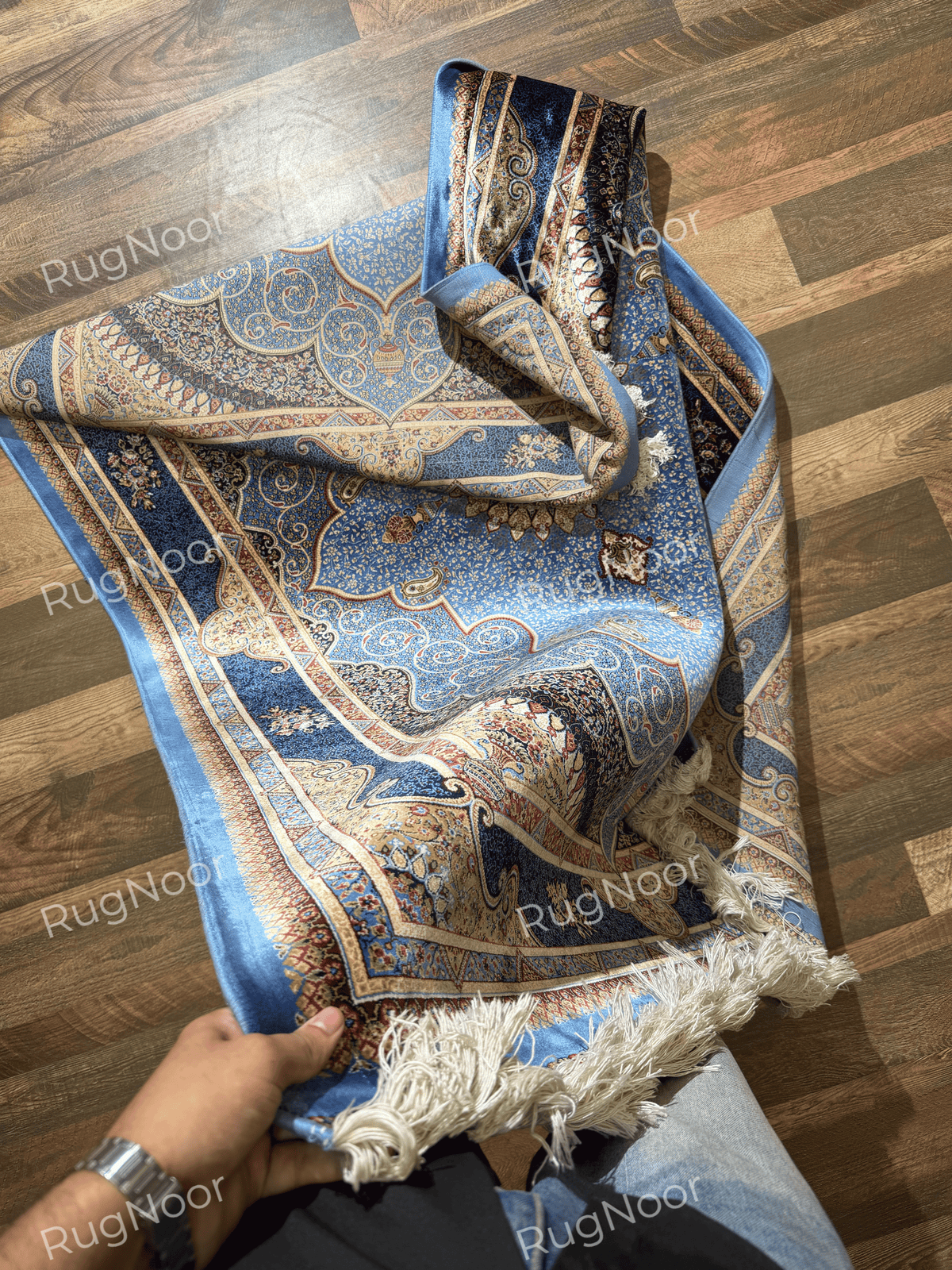 Yasamin folded rug showing its blue and gold pattern, underside, and ivory fringe.