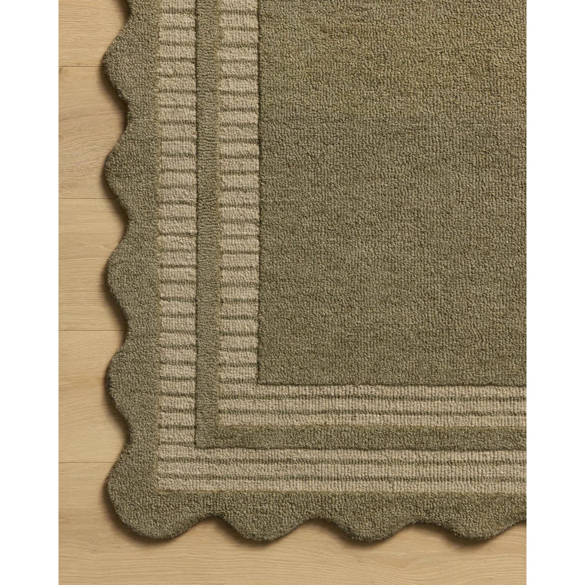 Textured green rug with scalloped edge on a wooden floor