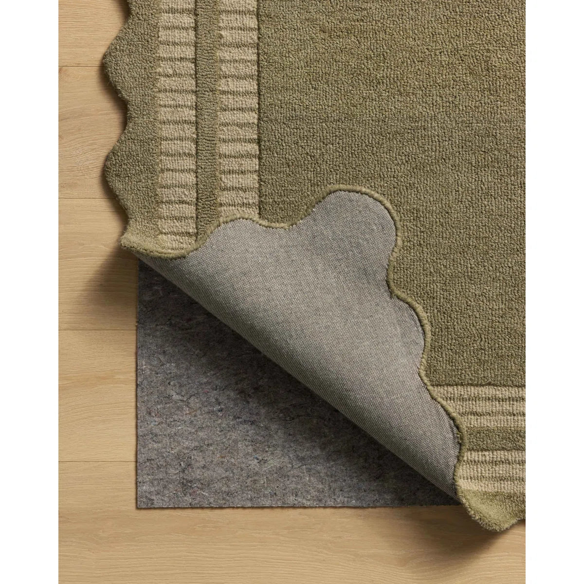 Green textured rug with gray underlay on a wooden floor