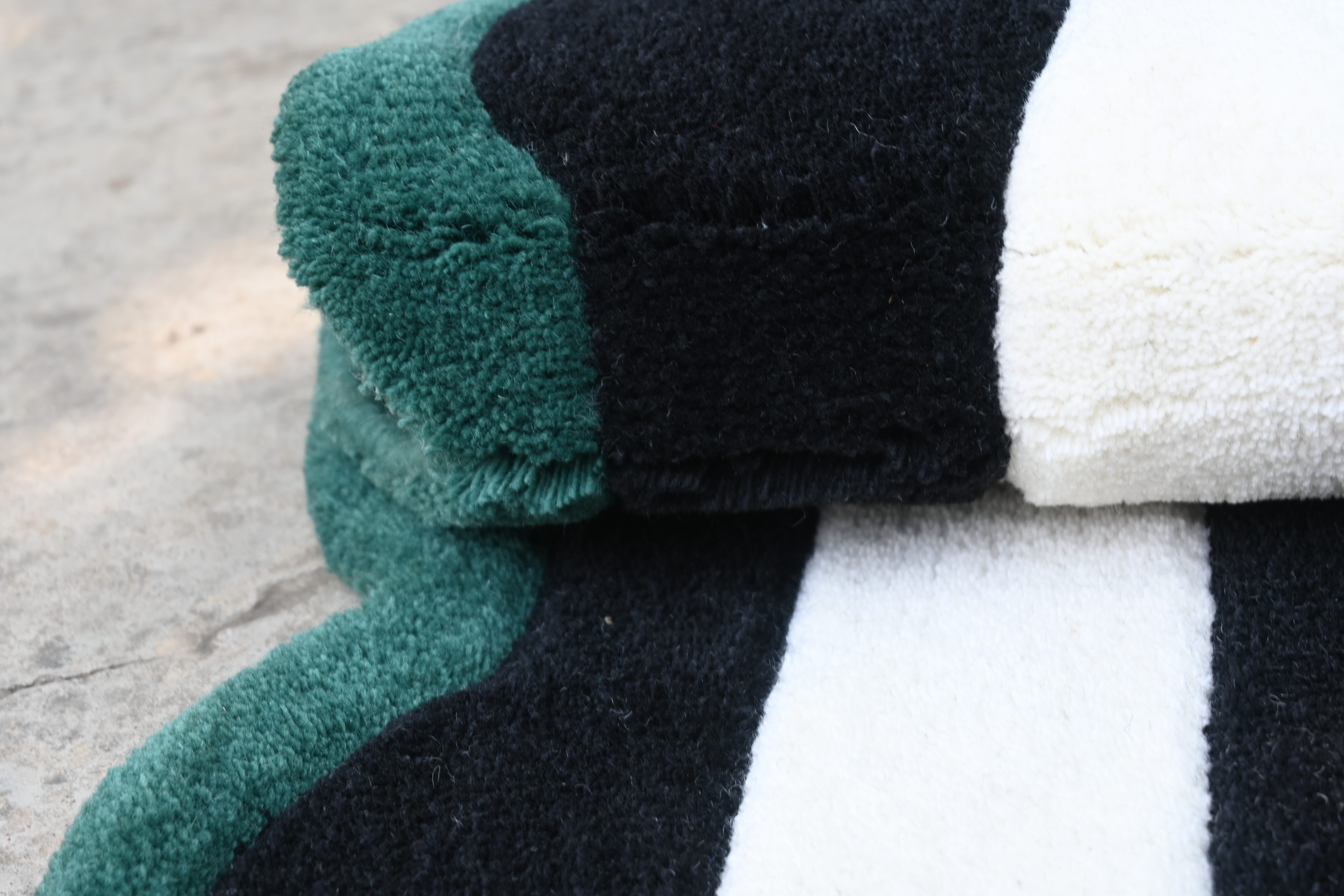 Close-up of a textured fabric with green, black, and white colors on a concrete surface.