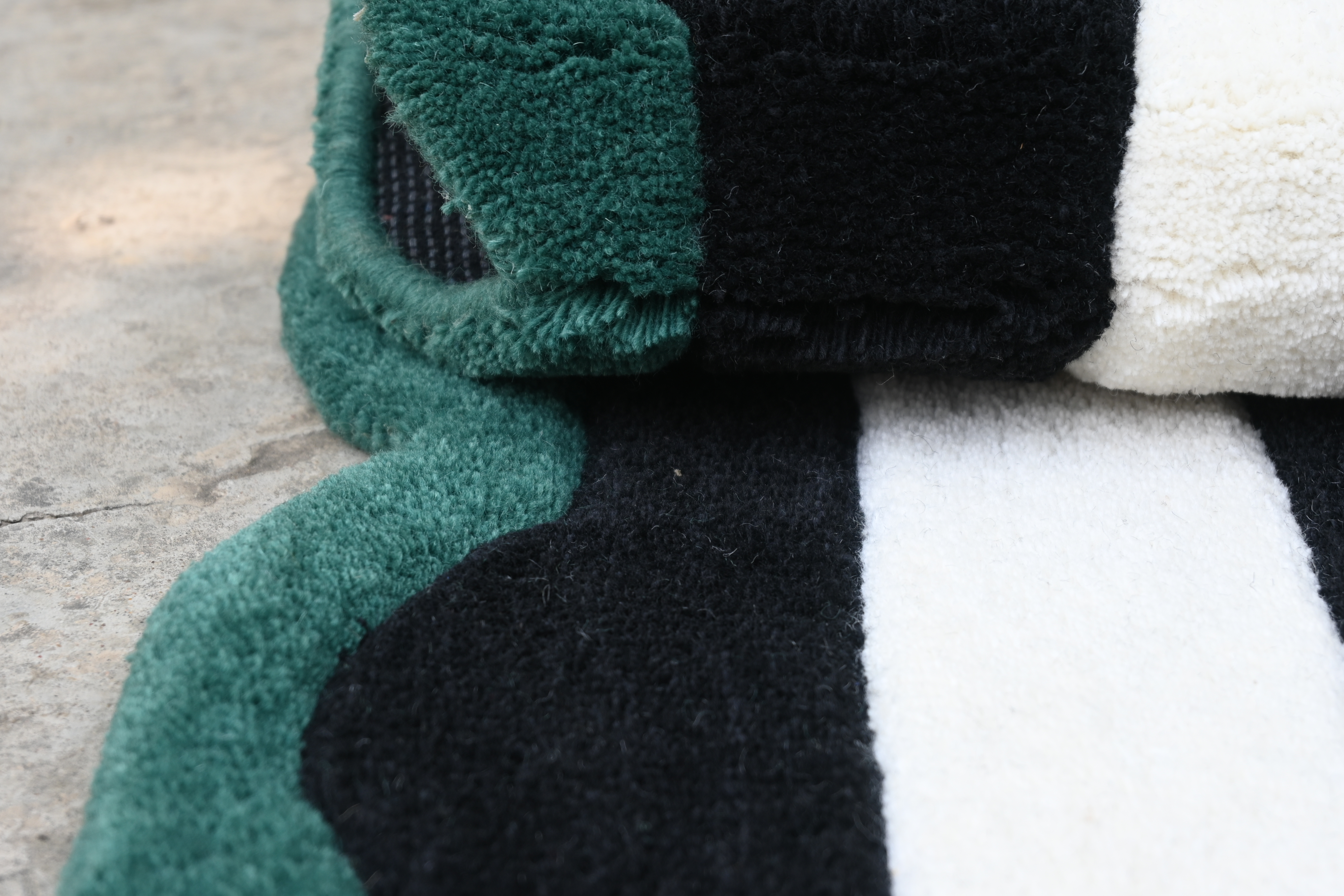 Close-up of a multicolored fabric with green, black, and white stripes on a textured surface.