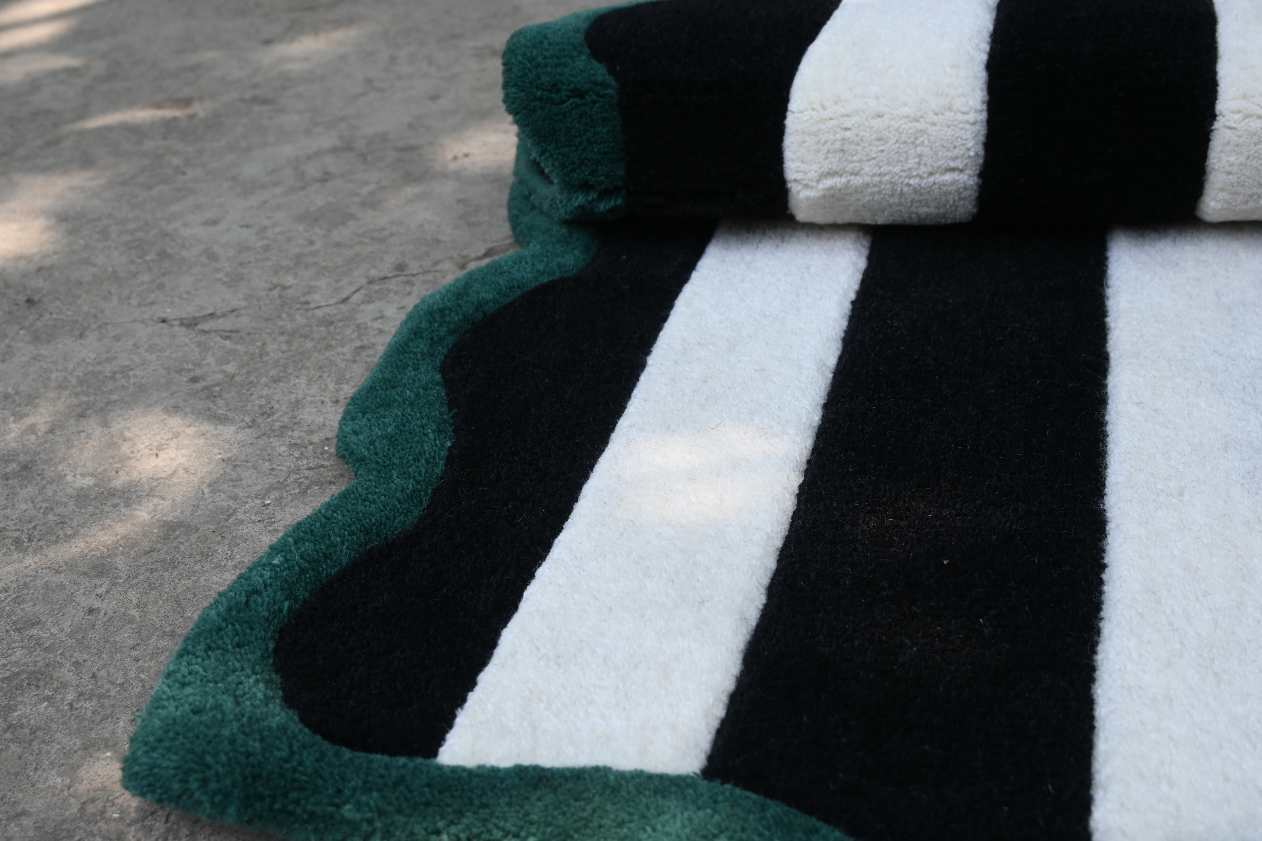 Close-up of a black, white, and green striped rug on a concrete floor.