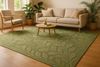 A beautifully styled living room with a hand-tufted green rug inspired by nature, featuring soft leafy patterns and earthy textures. The space has natural light pouring in through large windows, indoor plants placed around, and minimalist modern furniture in neutral tones. The rug should be the centerpiece, blending elegance with a calming, nature-inspired atmosphere. High detail, warm and inviting, lifestyle photography style.