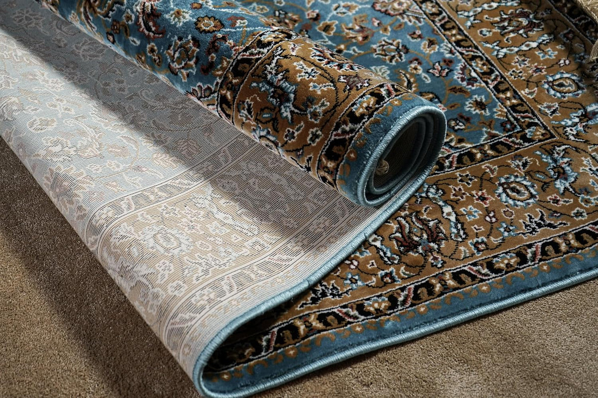 Almas Royal Floral Rug rolled back to reveal the patterned underside and finished blue edge