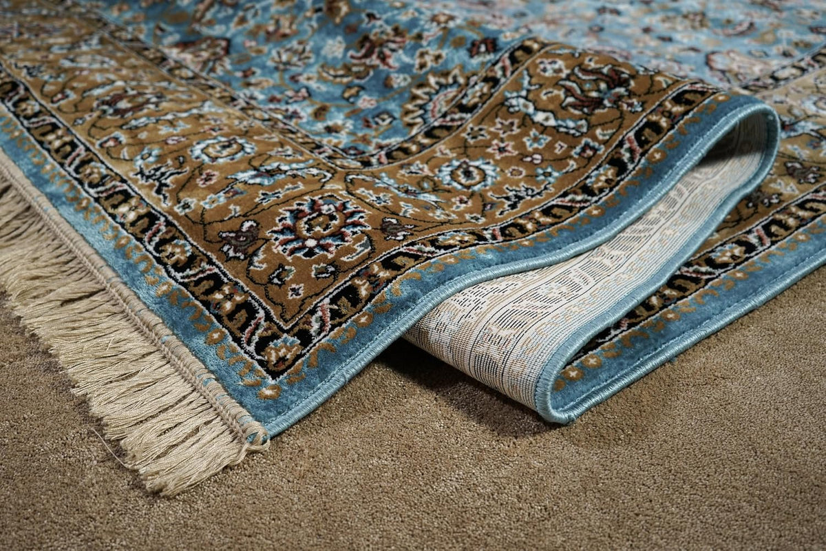 Almas Royal Floral Rug folded to show its floral border, blue edge and cream fringe