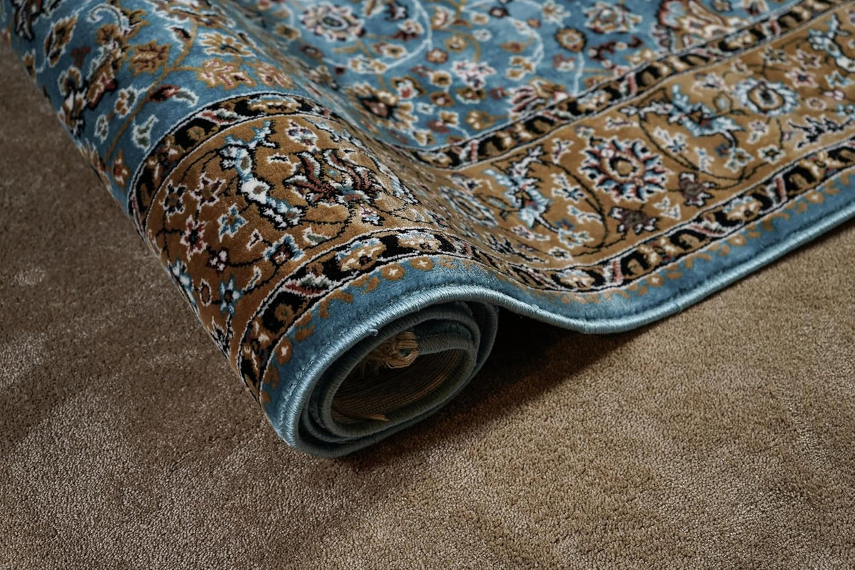 Almas Royal Floral Rug rolled to show its blue edge, floral pattern and layered construction