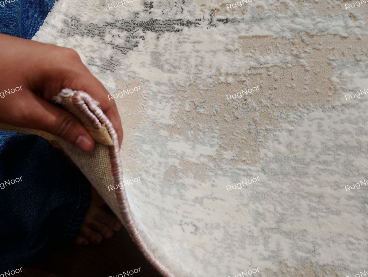 Lifted edge of the Amselle rug showing the front surface, pile and underside backing.