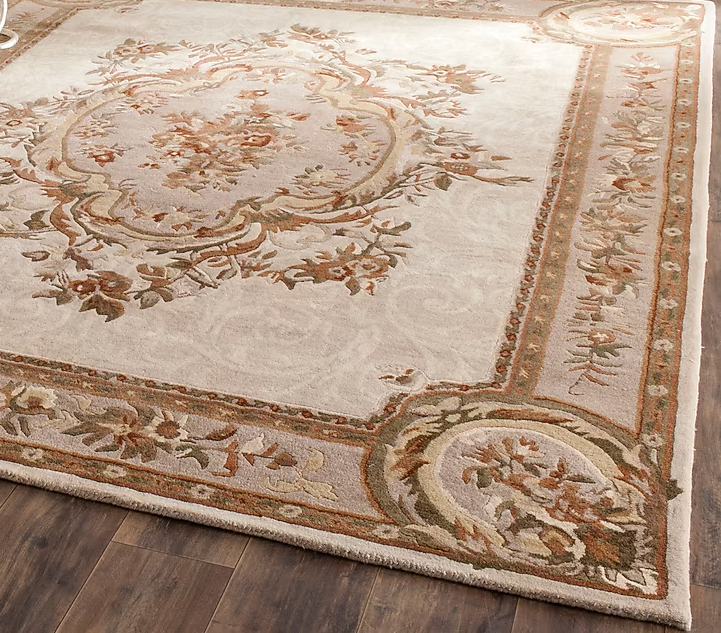 Close-up of Arenza wool rug showing its floral medallion, soft ivory field, and intricate beige, brown, and muted green details