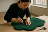 Artisan carefully carving and finishing a hand-tufted green rug with small tools, focus on edges and contours, natural daylight, fine details of craftsmanship, rich texture of wool, minimalist studio setting.