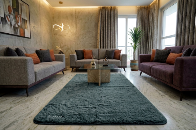 A large grey rabbit fur area rug in a modern living room setting, styled with gray and purple sofas, a glass coffee table, and neutral-toned walls.