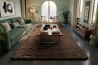A large coffee brown rabbit fur area rug styled in a modern living room setting with a green sofa, wooden coffee table, and dark gray tiled floor.