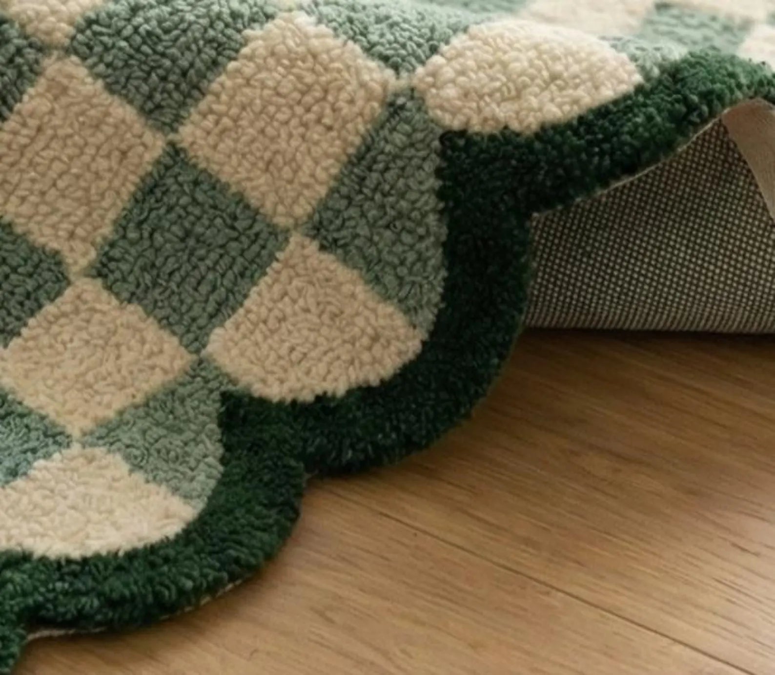 A close-up of a plush rug with a green and cream diamond pattern, shown partially rolled up on a light wood floor.