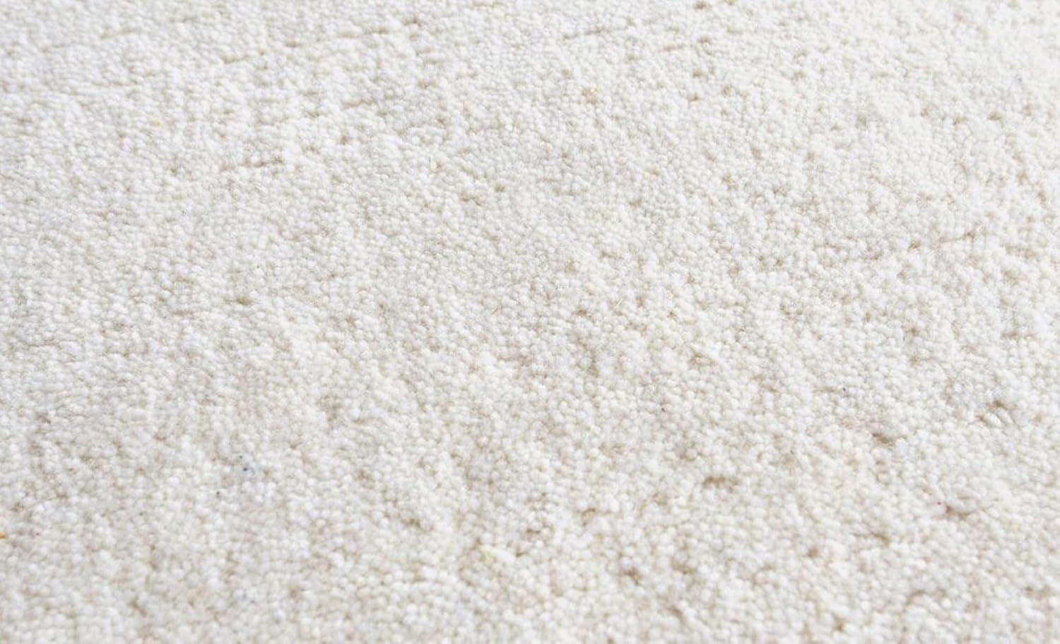 Close-up of dense white hand-tufted wool carpet pile texture