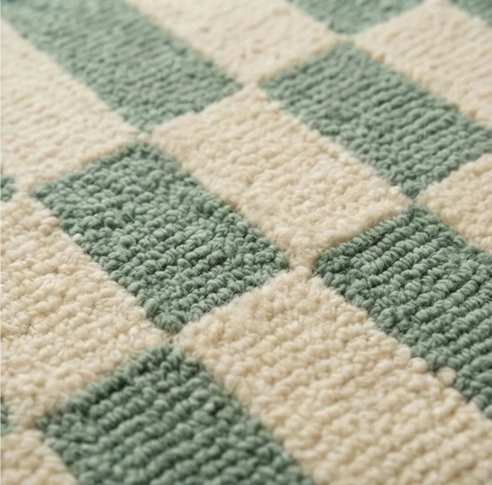 A close-up of a textured rug with a green and cream checkerboard pattern.