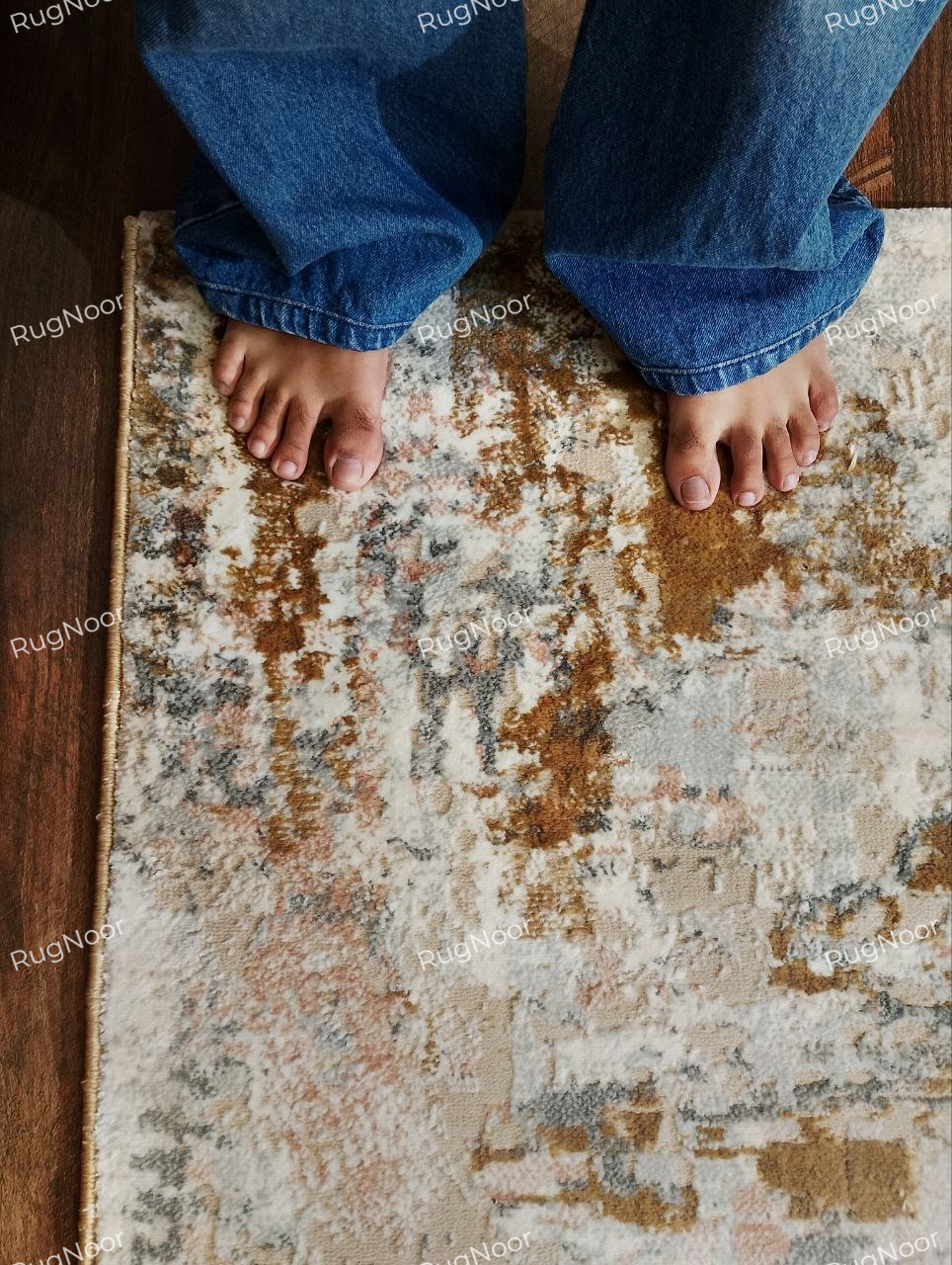 Close-up of the Crossfade rug's textured surface with a person standing at the edge to show its pile and scale.