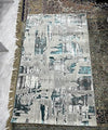 Grey and teal abstract pattern rug with fringe edges on marble floor