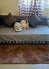 Soft brown faux fur rug in front of grey sofa with tassel throw