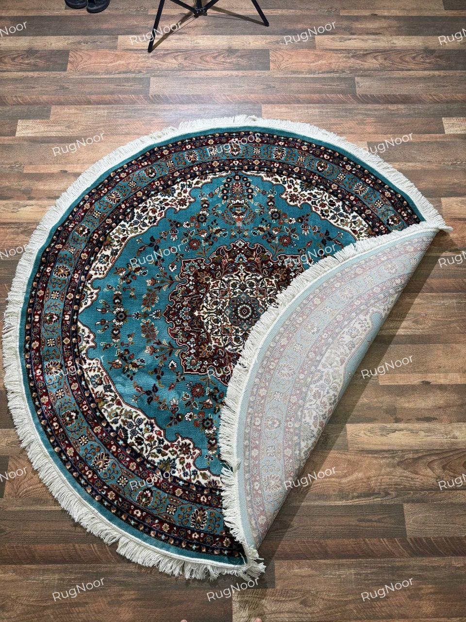 Folded corner of Fayruz round traditional rug showing the patterned underside, turquoise surface and ivory fringe - RugNoor