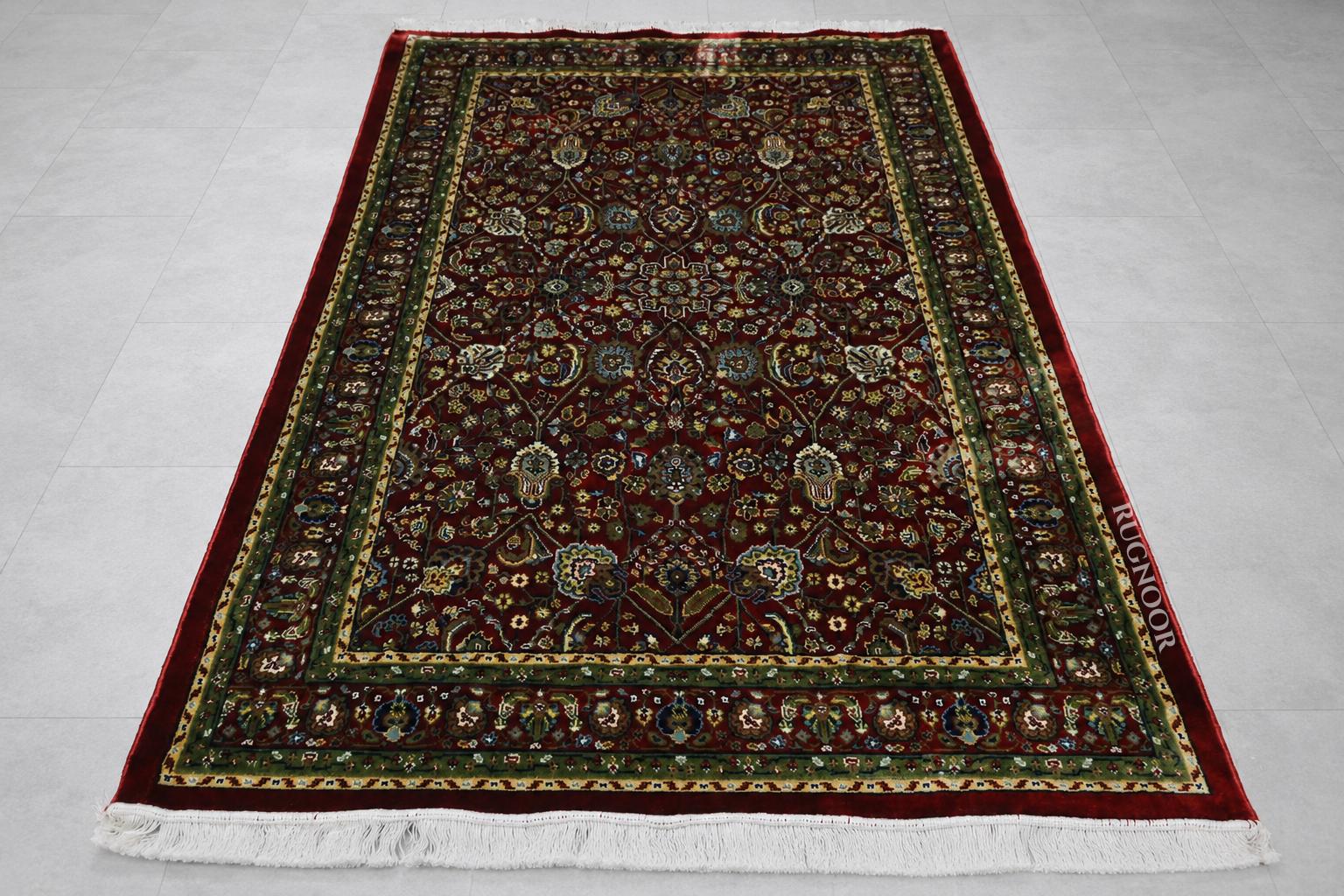 Firman Persian rug flat lay showing complete deep crimson field with forest green border and ivory fringe
