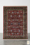 Firman Persian rug full view — deep crimson red base with forest green border, all-over floral arabesque pattern and ivory cotton fringe