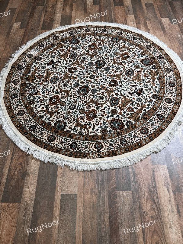 Full view of Zarqaya round ivory traditional rug with dense floral motifs, ornamental brown borders and fringe on a wooden floor - RugNoor