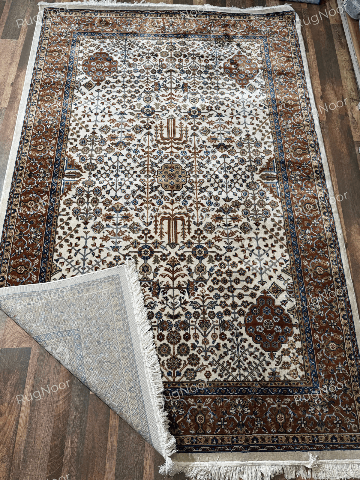Folded ivory traditional rug showing its patterned underside and finished edge - Ghazal RugNoor
