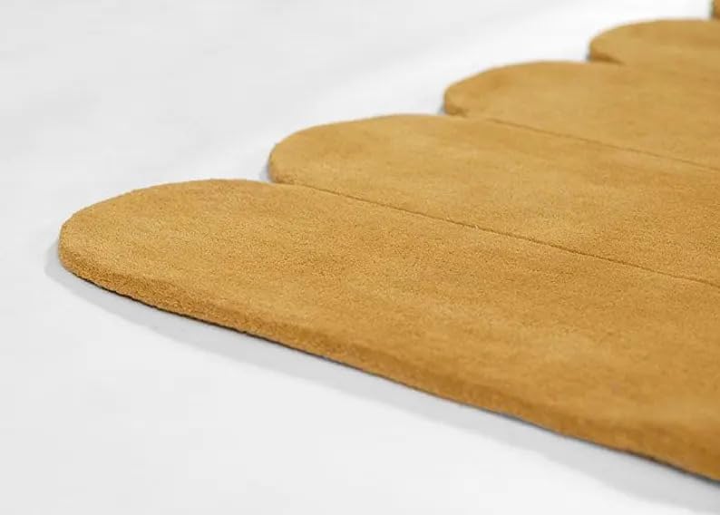 A close-up of a mustard yellow suede or suede-like mat with scalloped edges, shown on a clean white background.