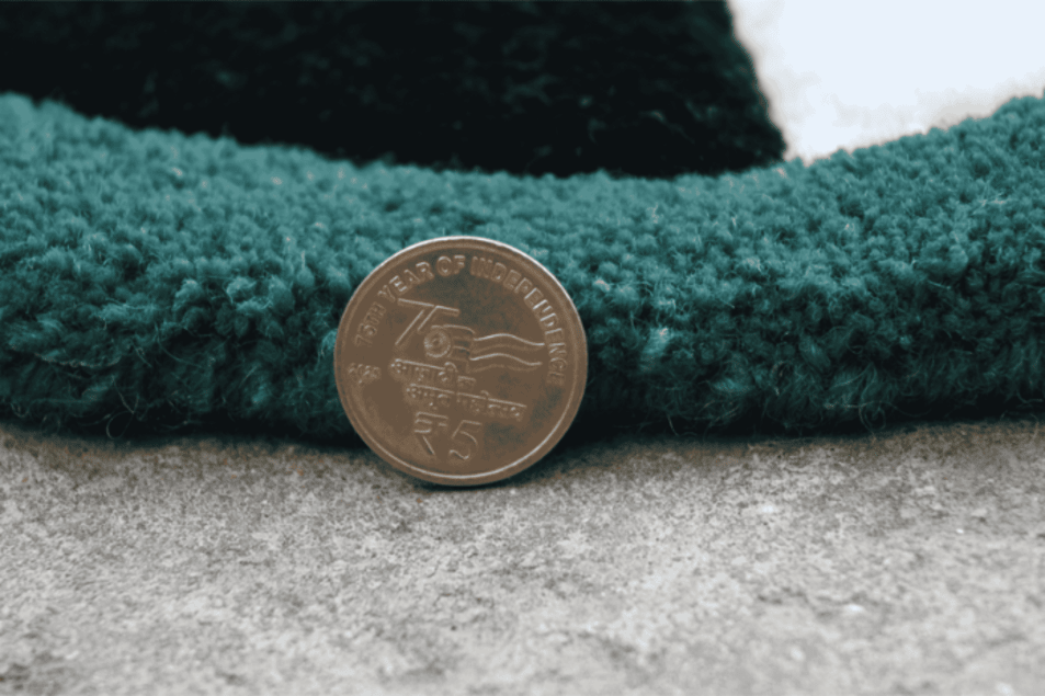 Hand-tufted green rug close-up with coin for pile thickness comparison – RugNoor