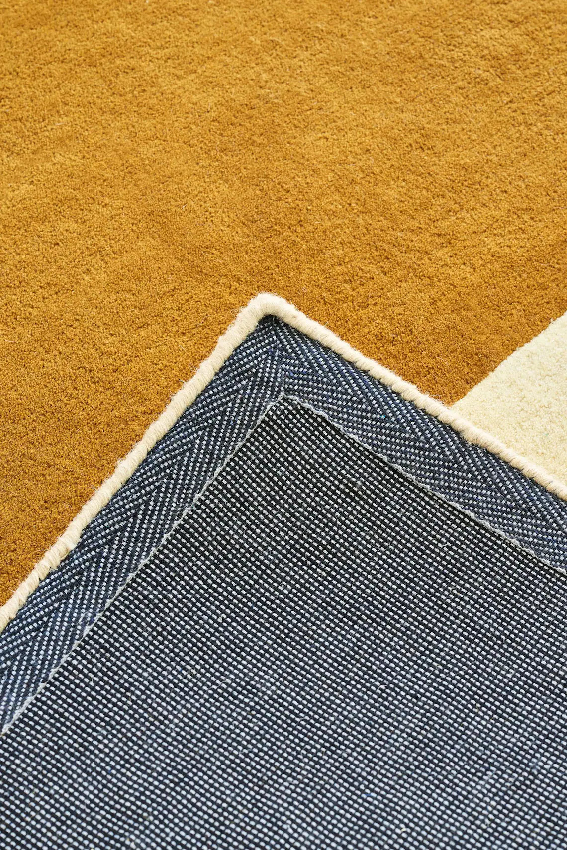 Folded view of plush mustard yellow rug corner with soft wool texture