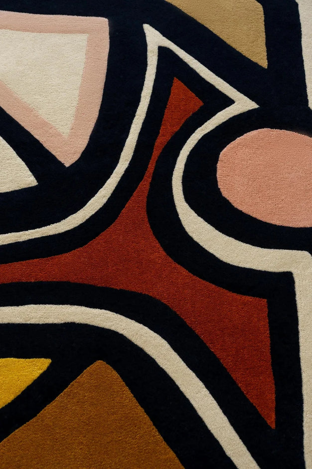 Detail of abstract pattern in red, black, cream, and mustard on designer rug