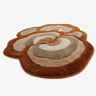 A plush, shaggy area rug with an organic, cloud-like shape featuring concentric layers in shades of brown, tan, and cream, shown on a plain white background.
