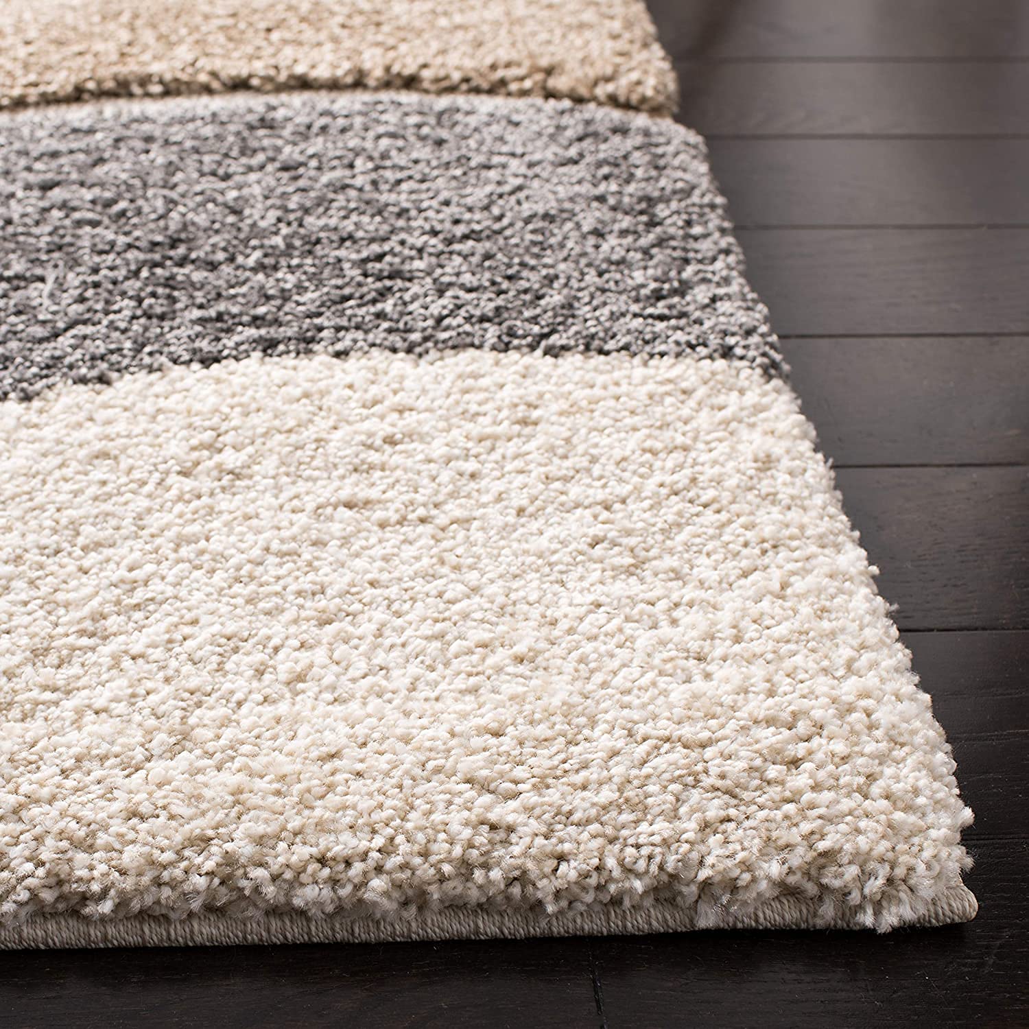 Striped rug with beige, gray, and white colors on a dark wooden floor.