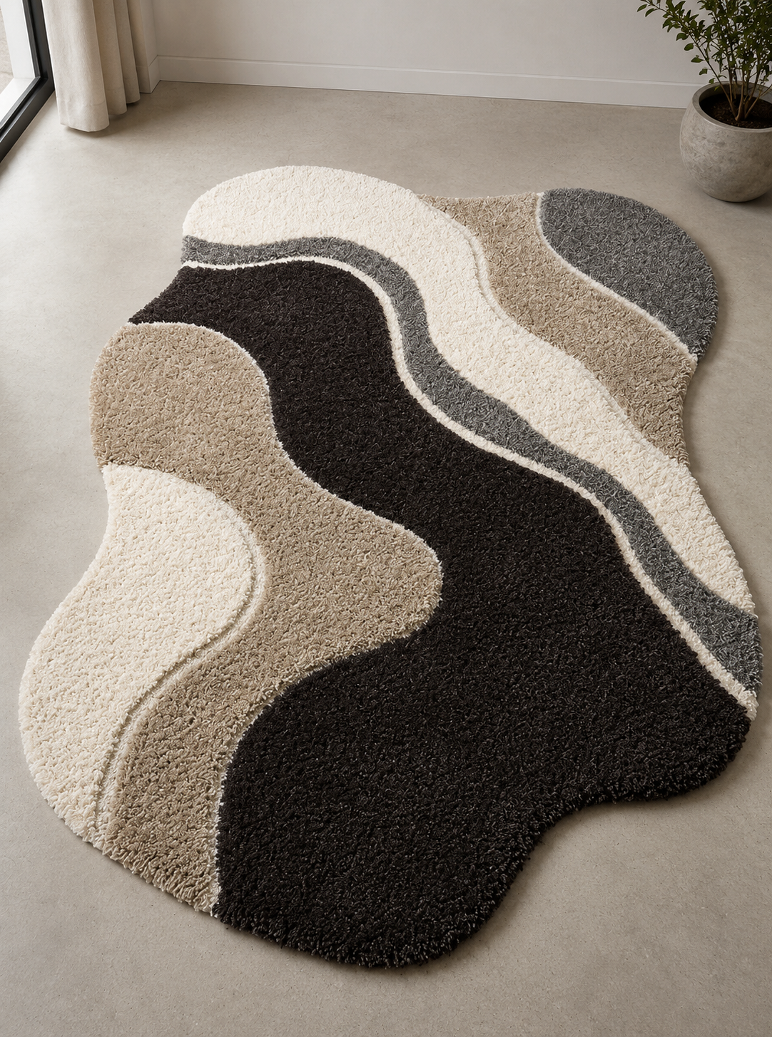 An abstract wavy area rug with a shaggy texture in cream, beige, brown, and charcoal gray, styled on a light gray concrete floor in a minimalist room.