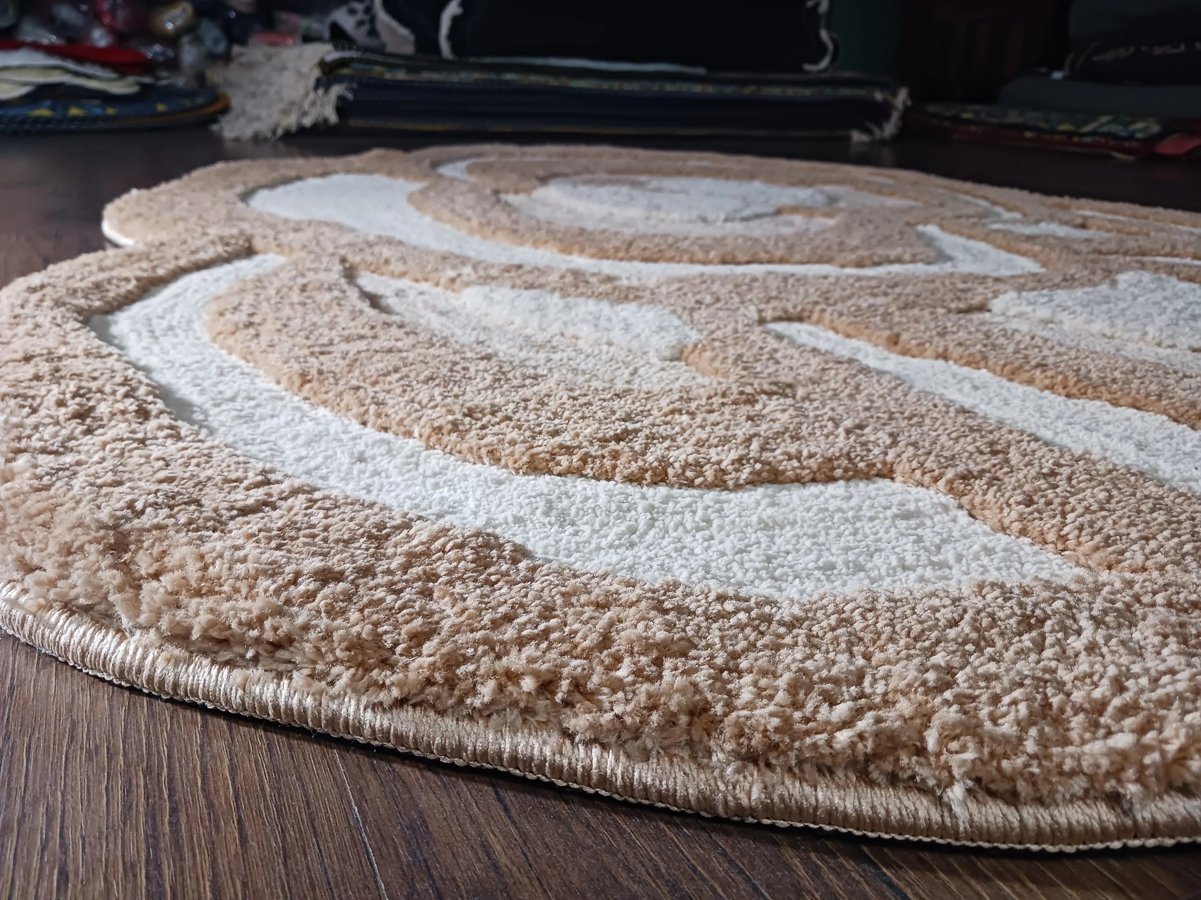 Round beige rug with a textured pattern on a wooden floor
