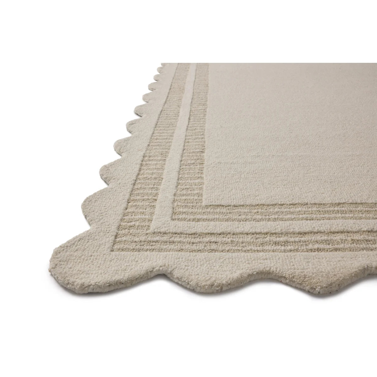 Close-up of a textured area rug corner showing a scalloped edge and raised striped border in a warm off-white or light beige tone on a white background.