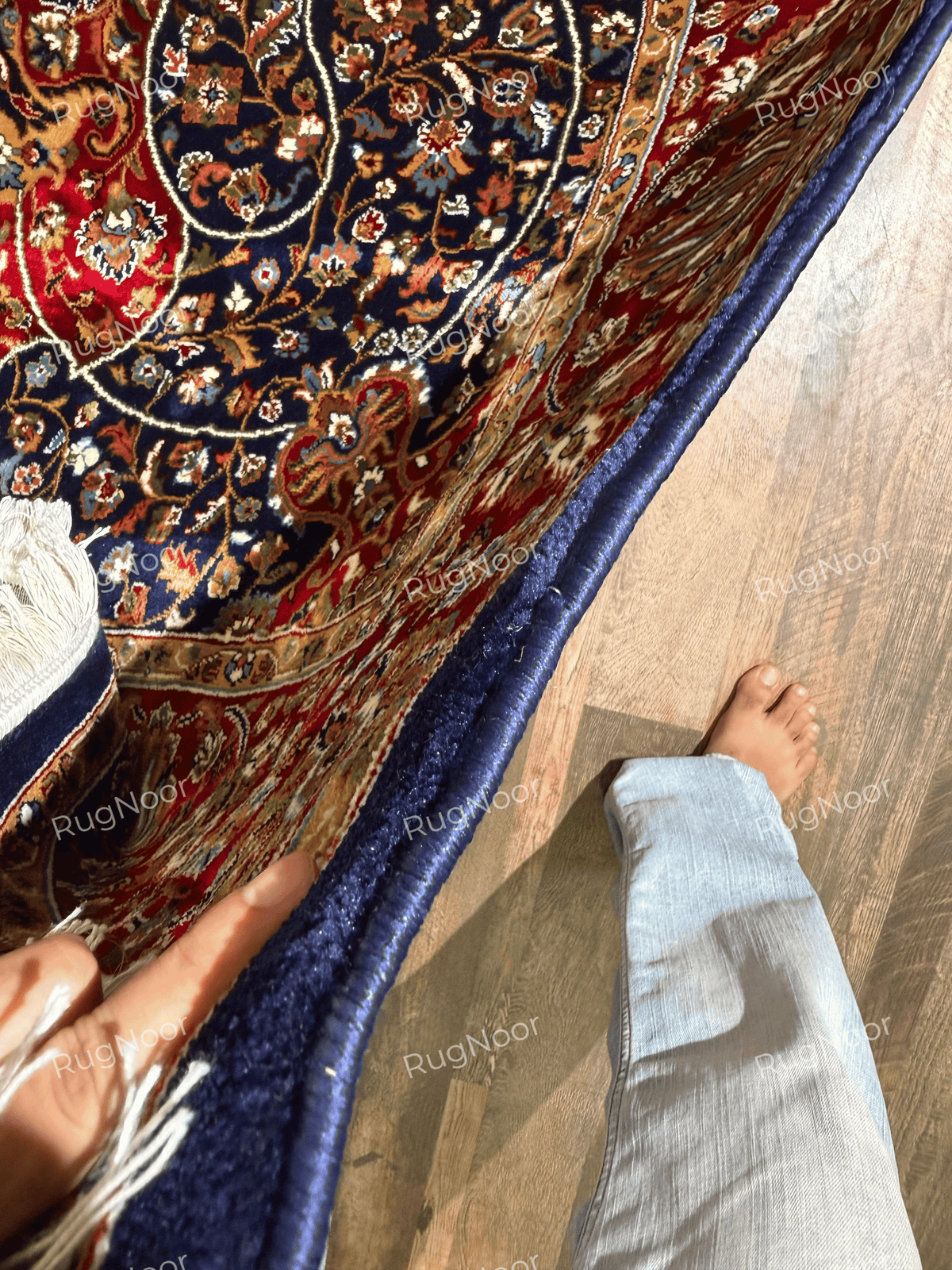 Folded Jouri rug edge showing navy binding, pile and finished border - RugNoor
