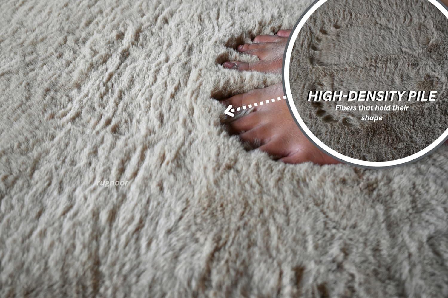Close-up of a light beige faux fur rug with a foot pressing into the plush pile. The image highlights the high-density pile and fibers that hold their shape.