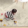 Child playing on a soft beige rabbit fur carpet with toys