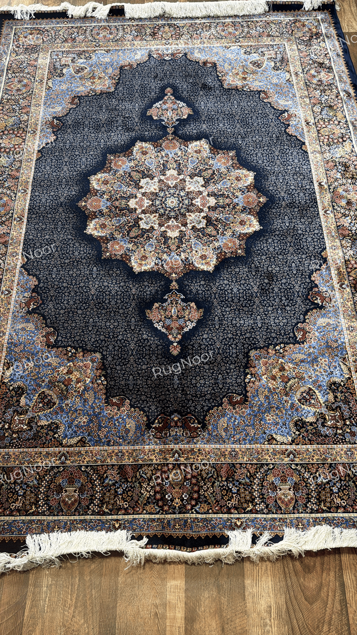 Overhead view of the complete carpet with a navy field, ornate floral medallion, and multicolour traditional borders by RugNoor