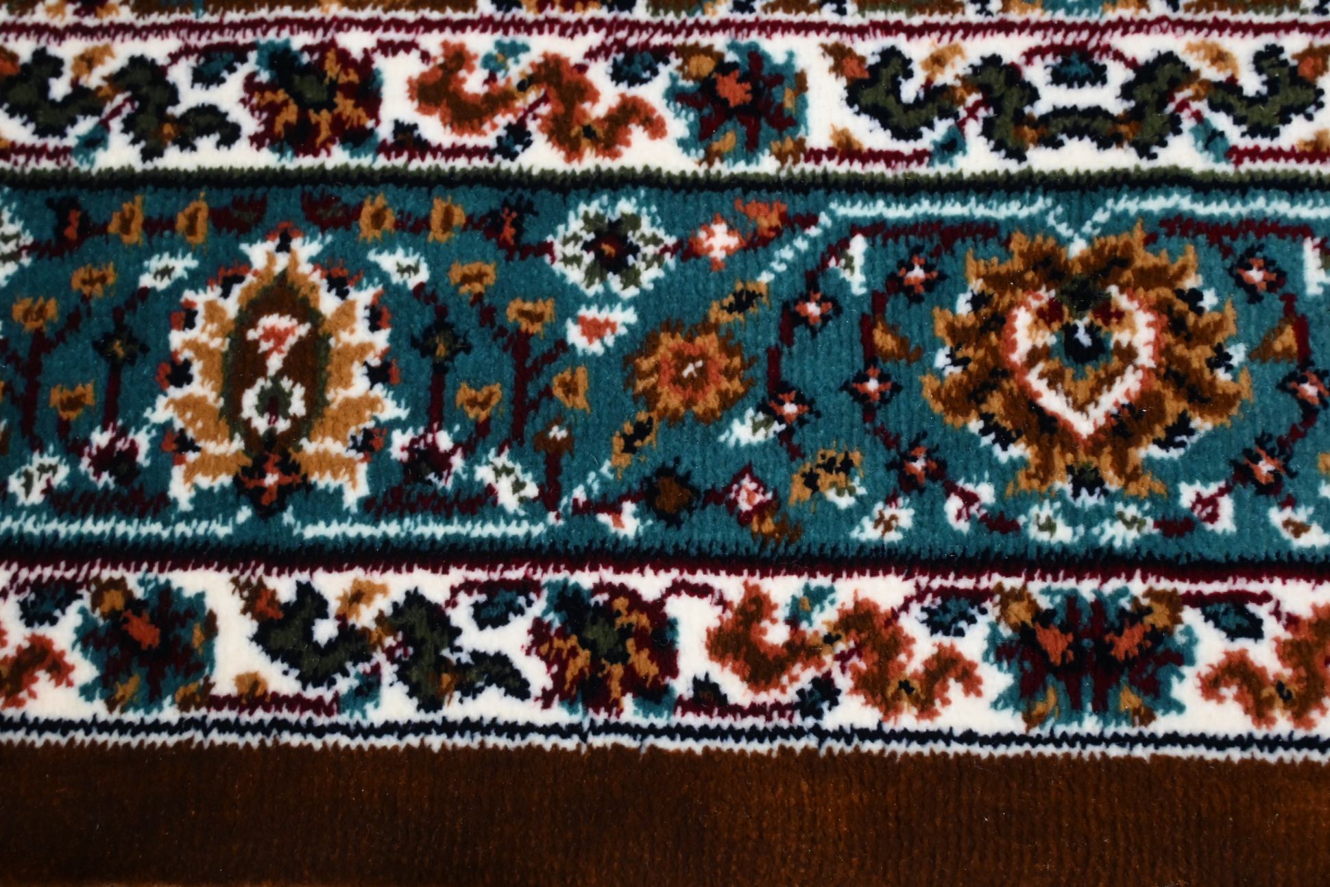 Close-up of Naqsh Persian rug teal border stripe showing layered floral vine motifs on ivory background