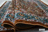 Naqsh Persian rug folded showing soft acrylic wool pile, deep teal border detail and plush comfortable texture