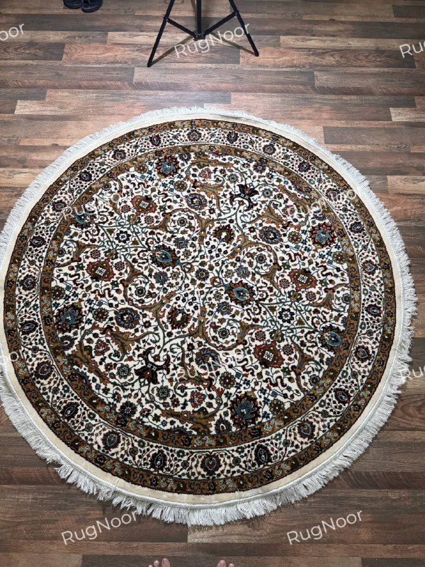 Full overhead view of Zarqaya round Persian-inspired floral rug in ivory, brown and teal with decorative borders and fringe - RugNoor