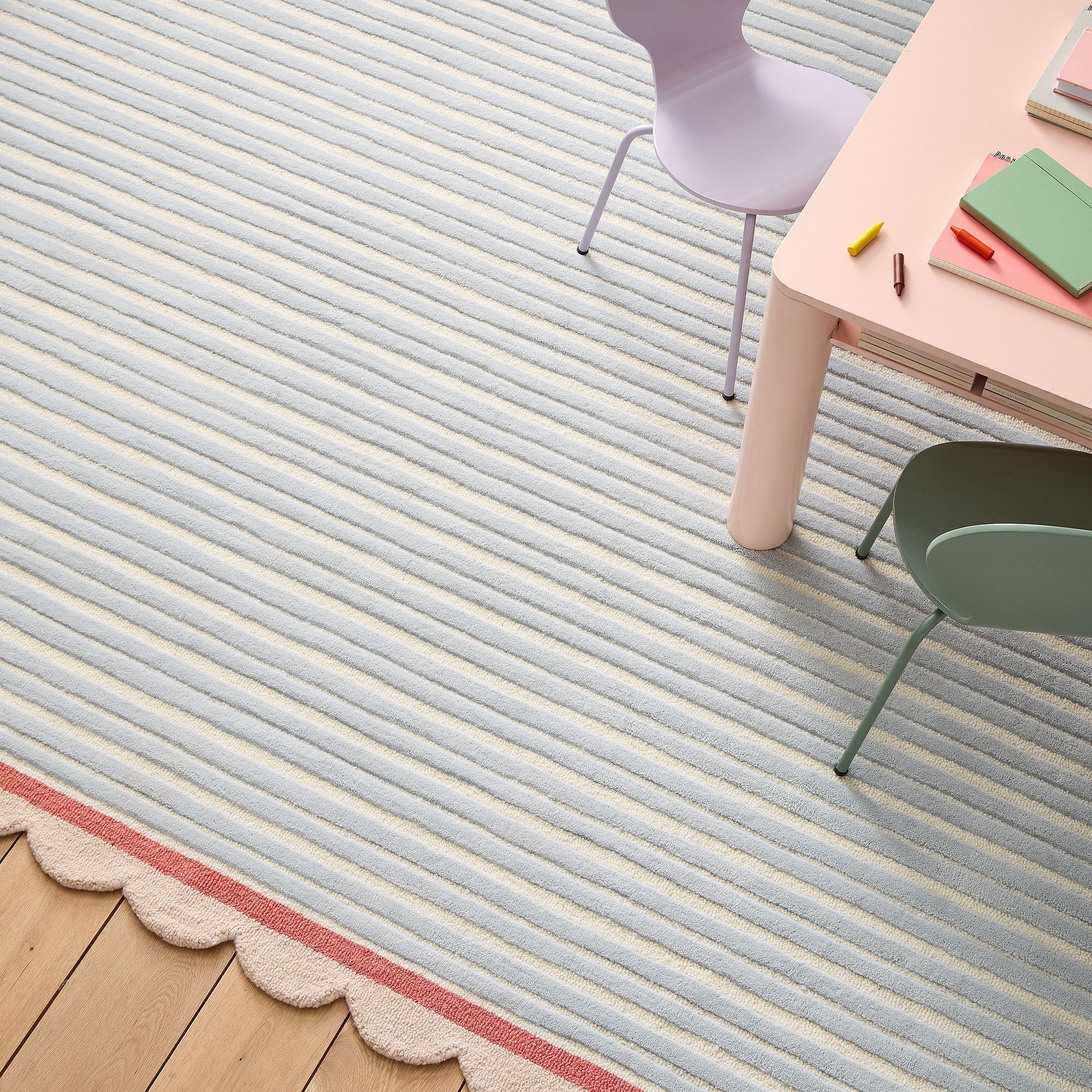 Striped rug with a scalloped edge in a room with a table and chairs.