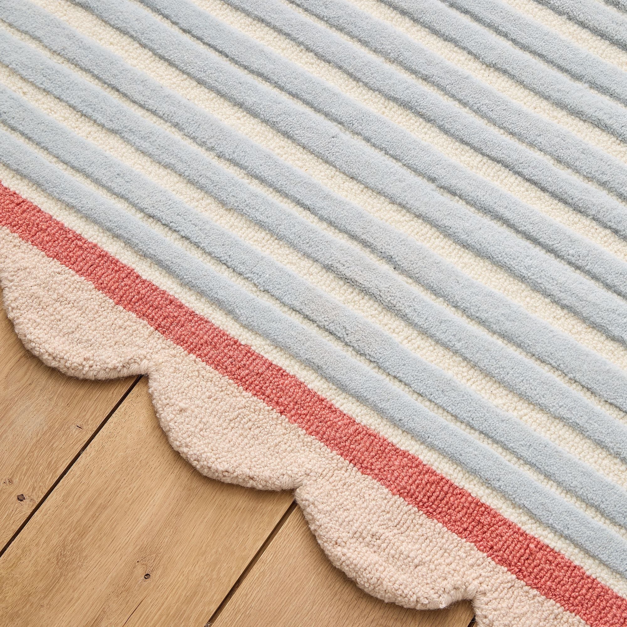 Striped rug with red, blue, and beige colors on a wooden floor.