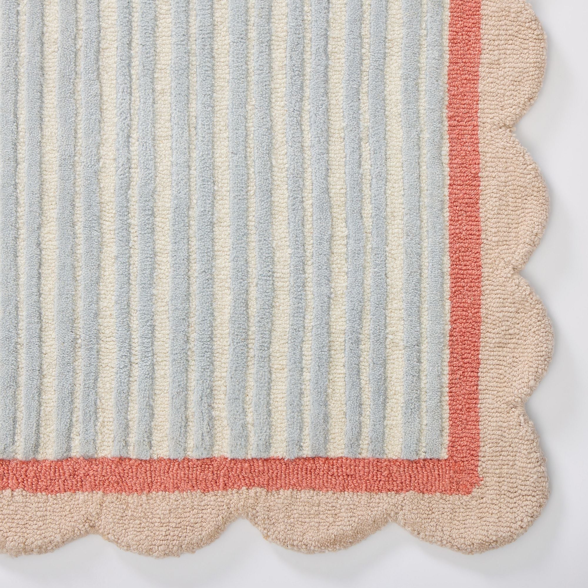 Striped rug with scalloped edge in pastel colors on a white background