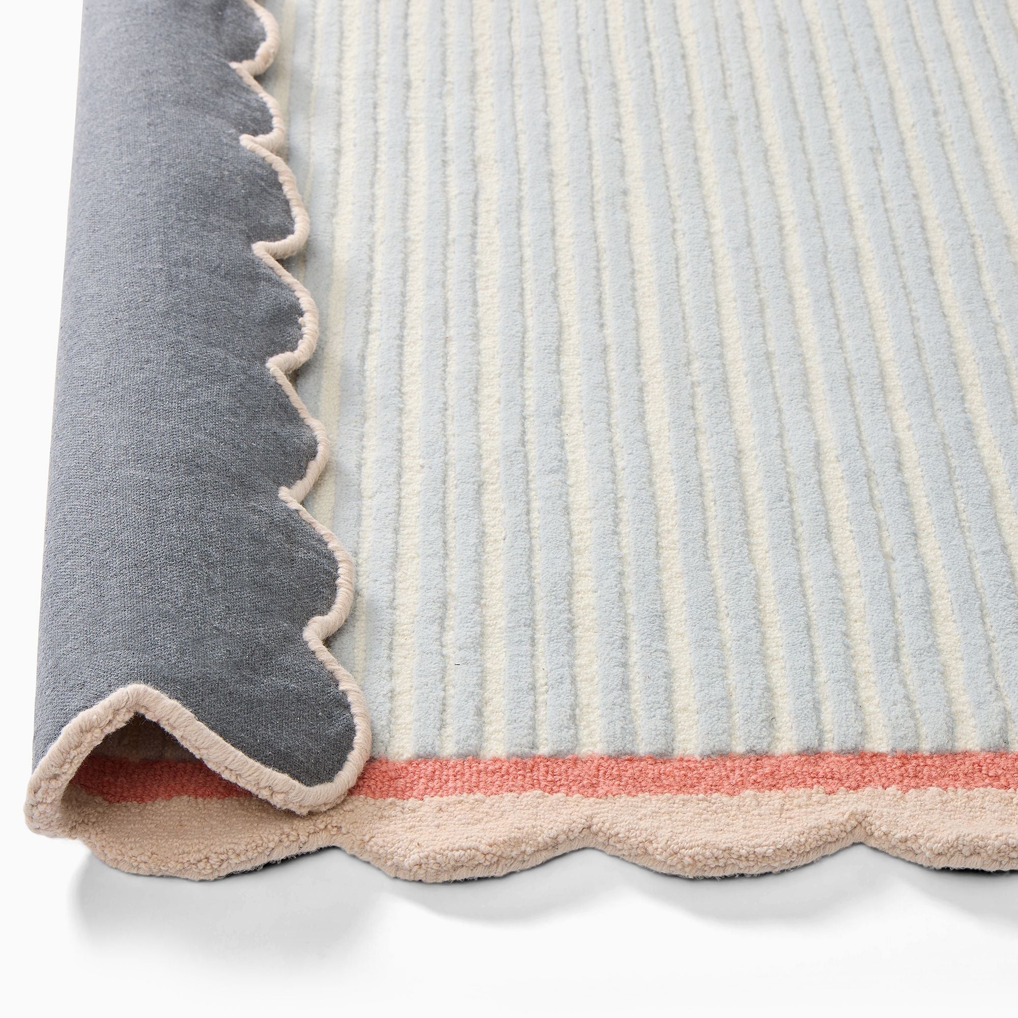 Close-up of a textured rug with a scalloped edge on a white background