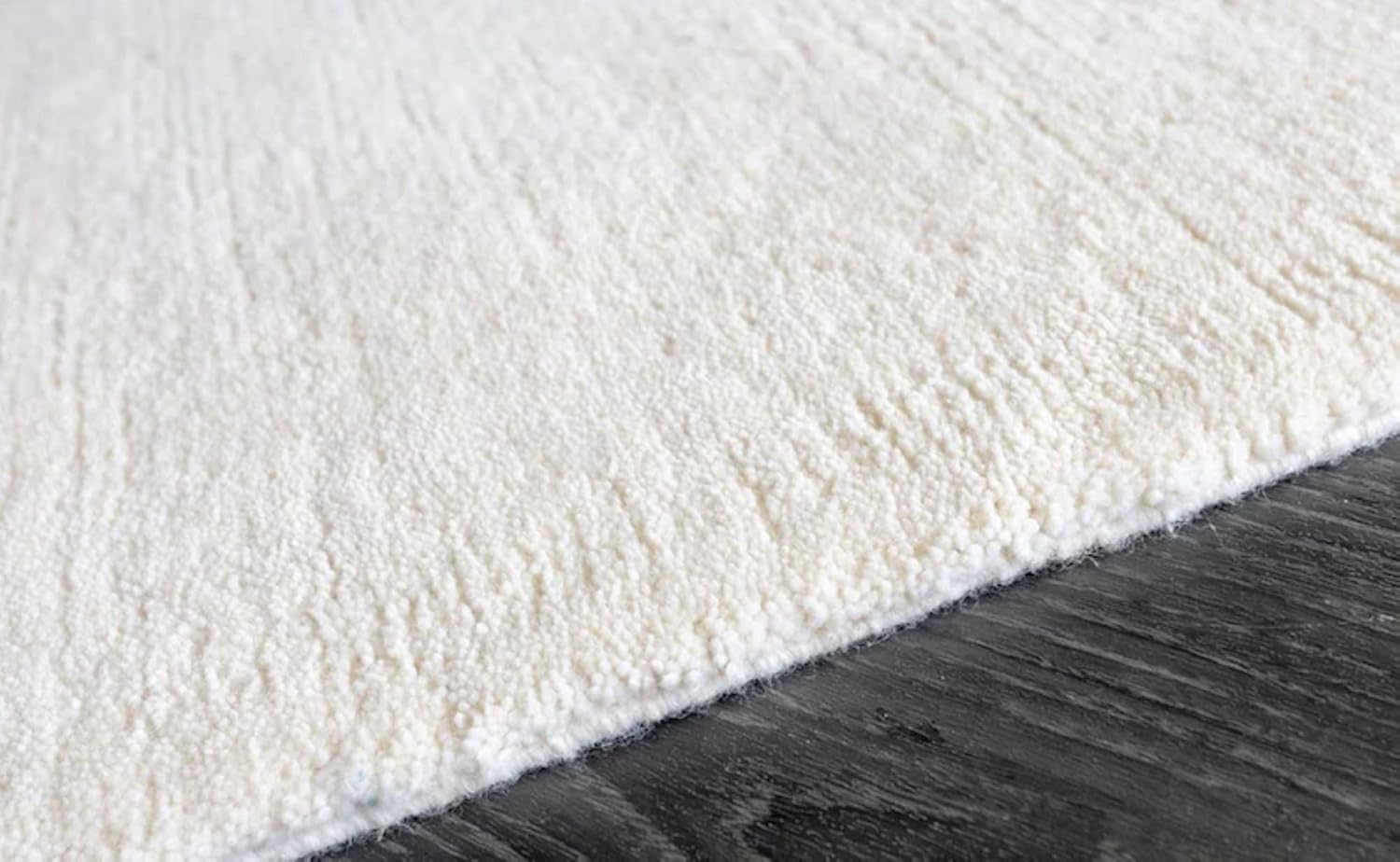 Hand-tufted white wool rug edge detail showing plush pile and finished binding
