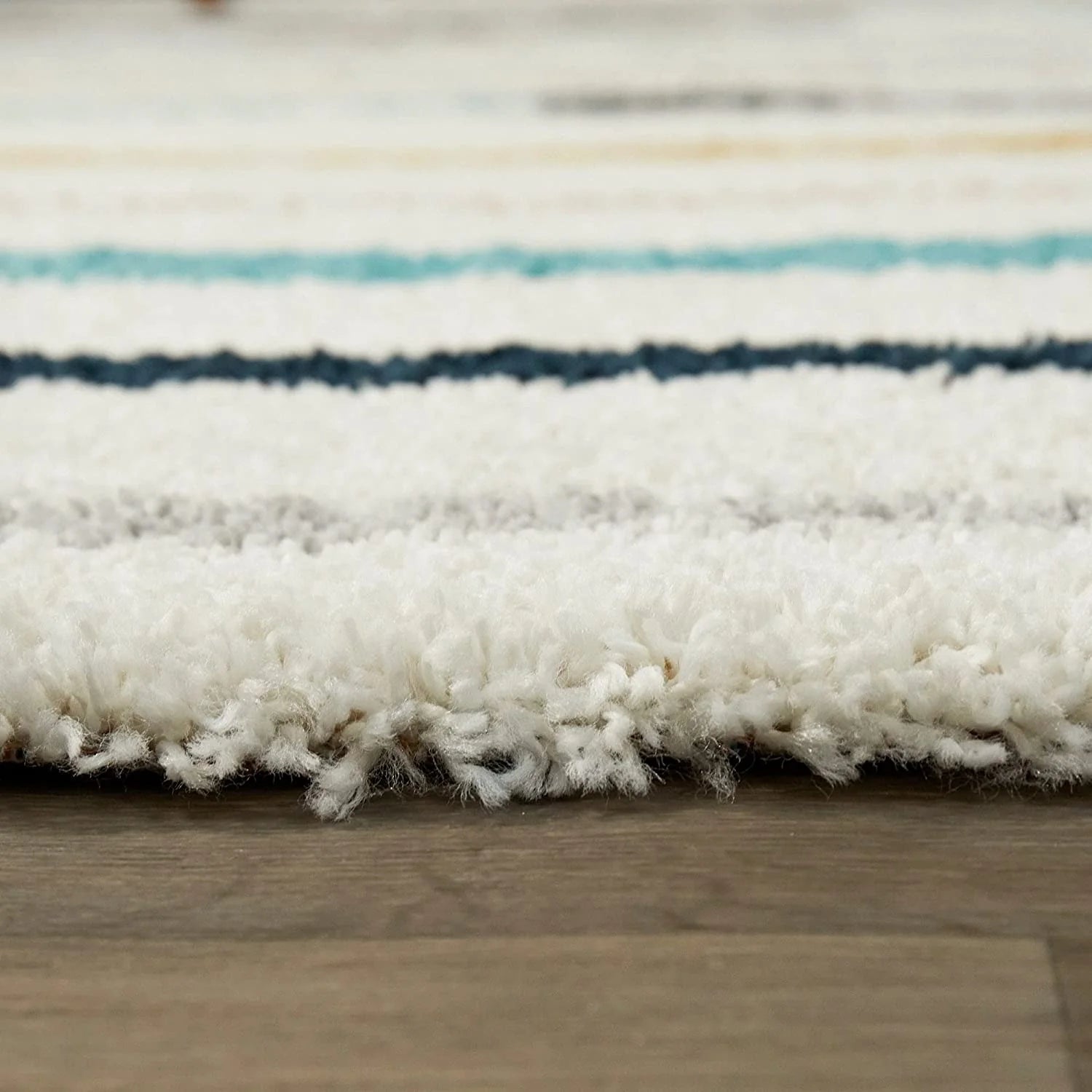 Close-up of a textured rug with horizontal stripes on a wooden floor.