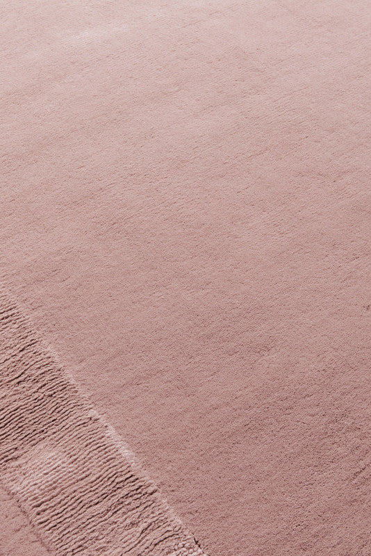 Close-up of blush pink hand-tufted wool rug showing border texture detail